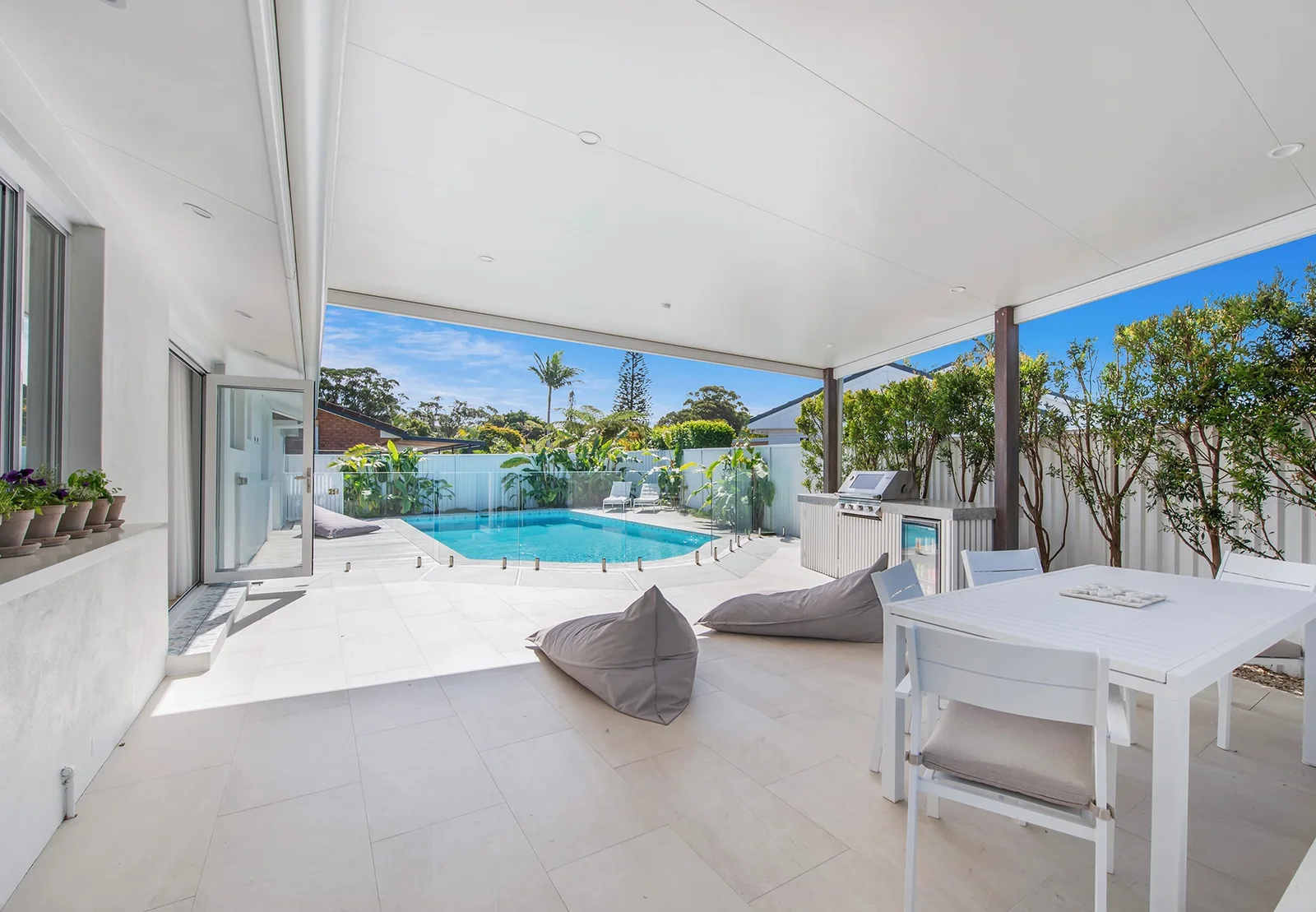 Sunlit private pool beyond the covered alfresco dining area and built-in barbecue