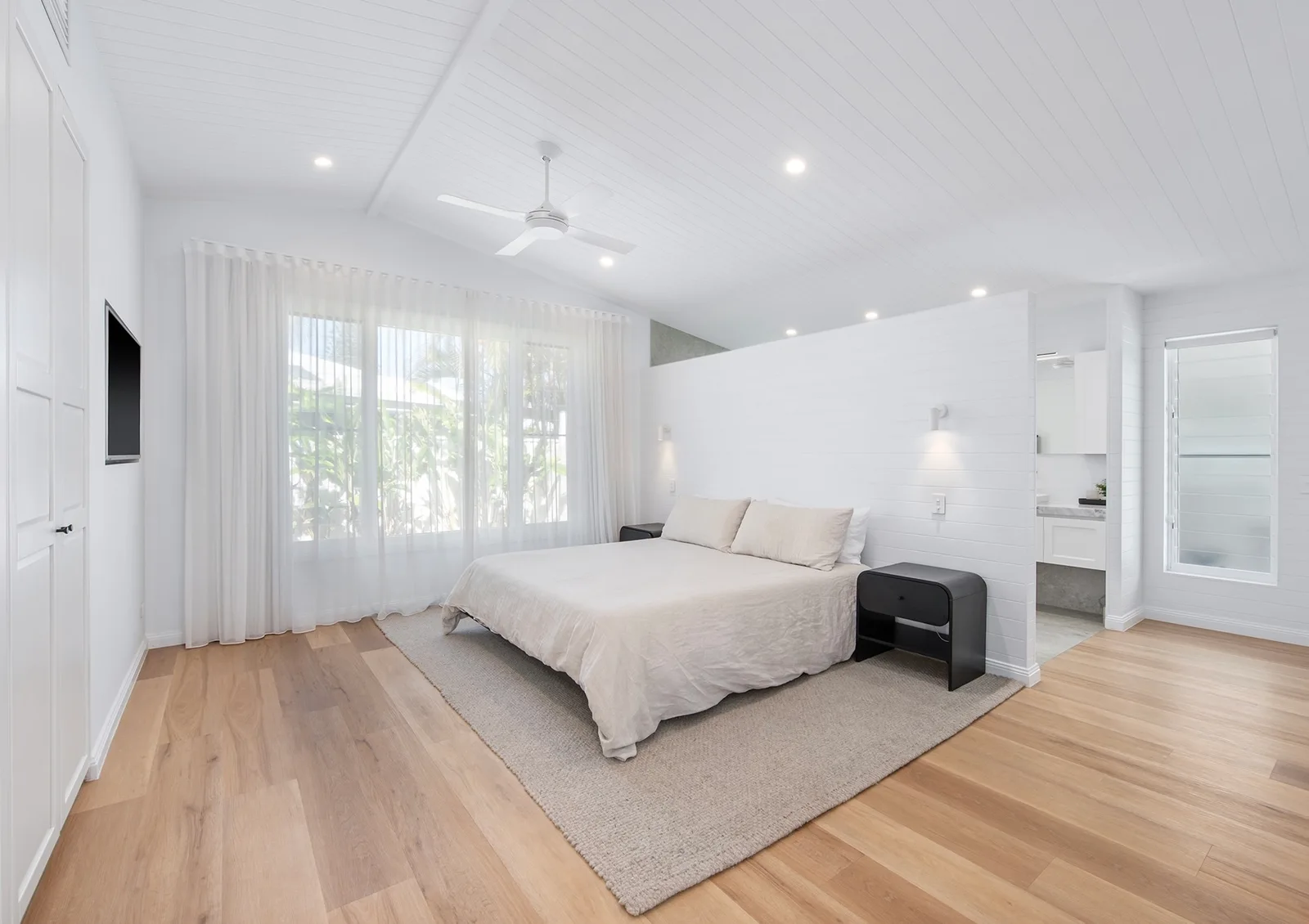 Light-filled master bedroom with vaulted ceilings, soft linen and an adjoining ensuite