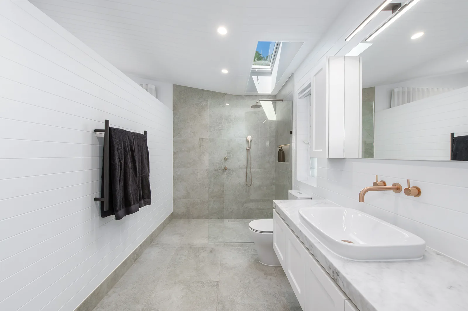 Modern ensuite with natural light falling through a skylight into the walk-in shower