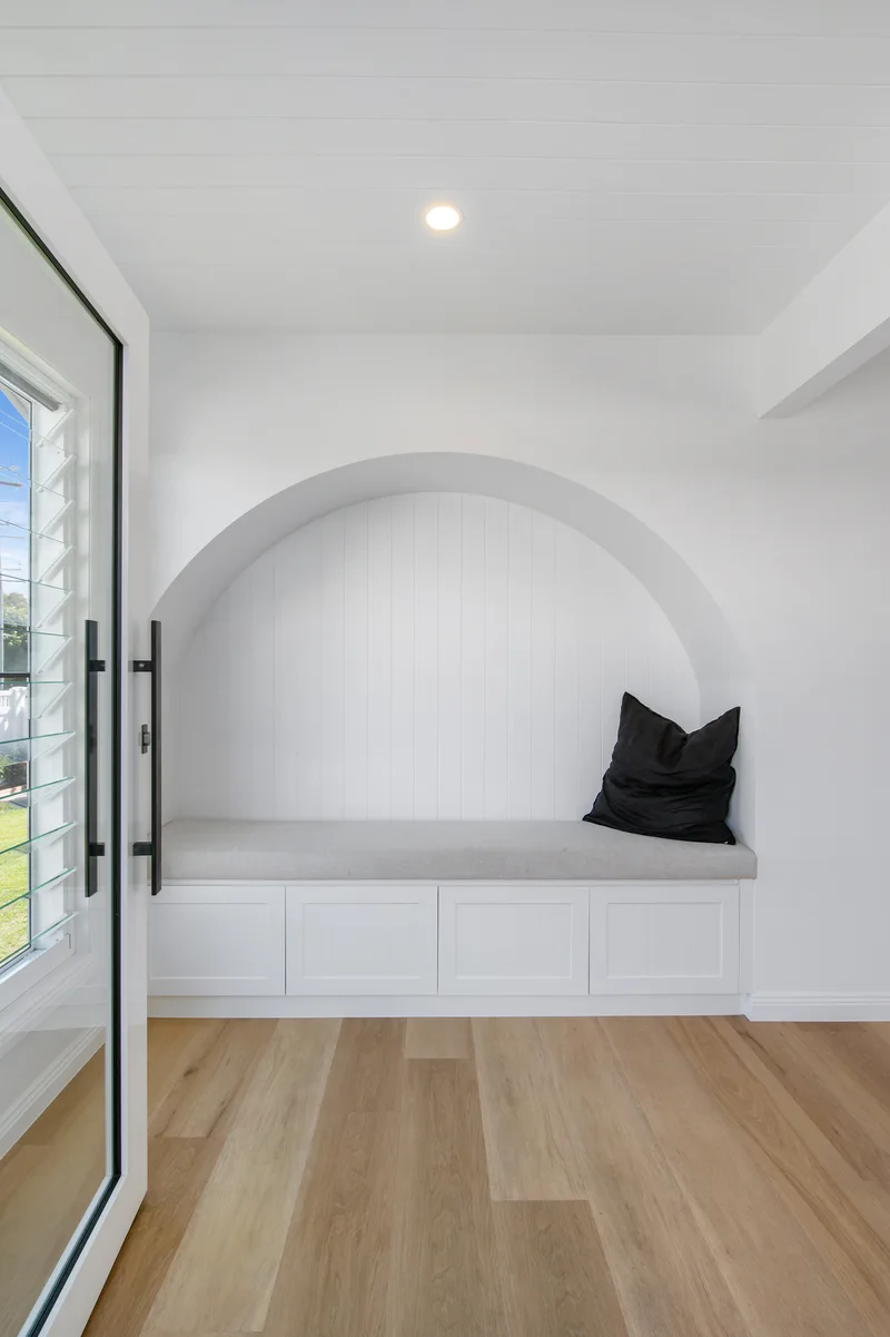 Arched entry nook with a linen-covered seat and timber floors